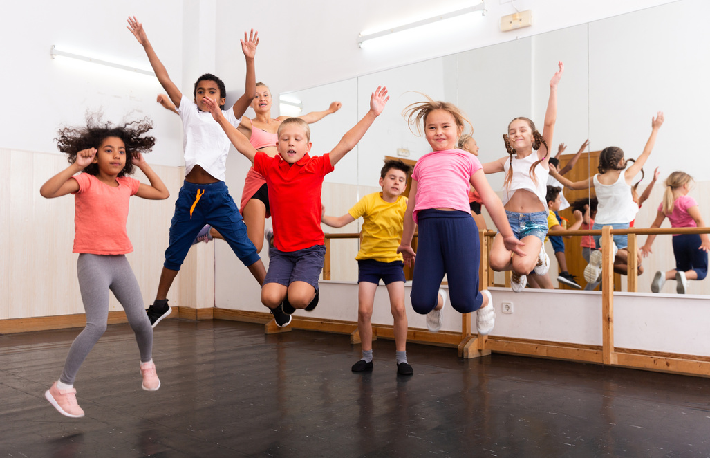 Happy sporty kids jumping together in dance studio