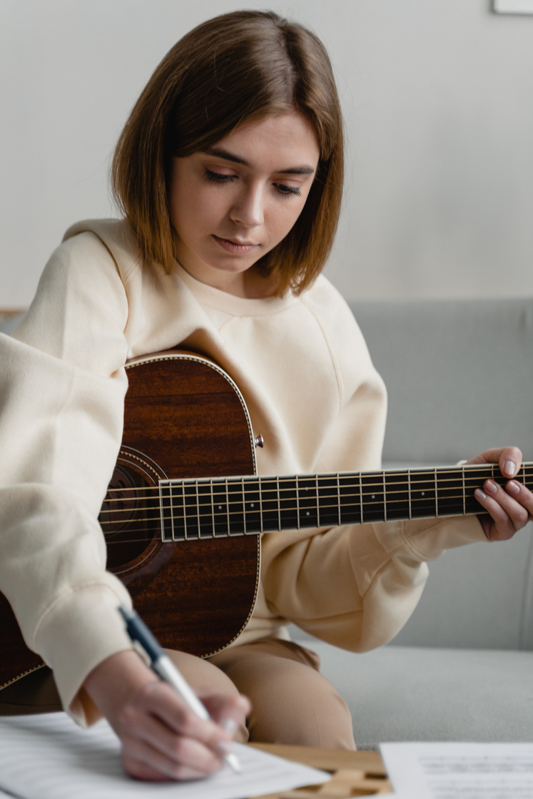 Young Woman Holding a Guitar and Writing
